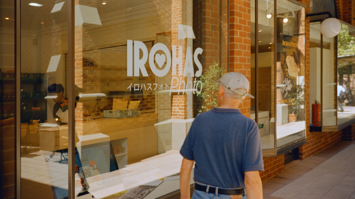 A passer-by outside the warm, sunlit windows of Irohas Photo in Perth