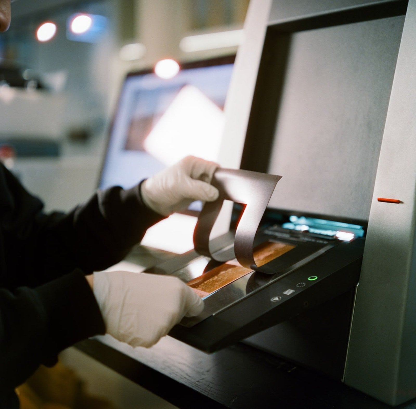 Film technician loading 35mm negatives into a Noritsu scanner at Irohas Photo Australia